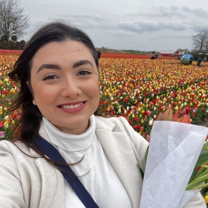 Gabriela Bordin, criadora da Up Travel Park, sorrindo em um campo de tulipas nos Países Baixos